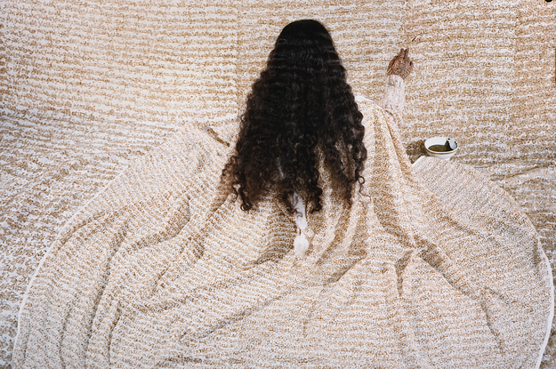 A long haired woman in a robe paints a wall with the same pattern