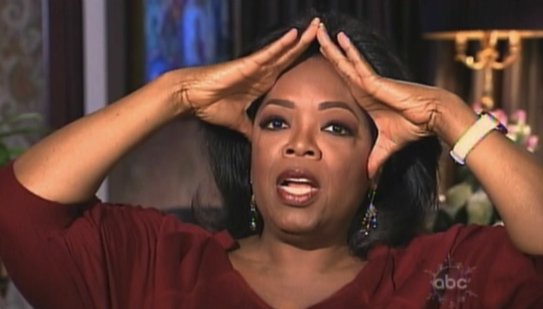 Oprah looking shocked with her hands cupping her forehead