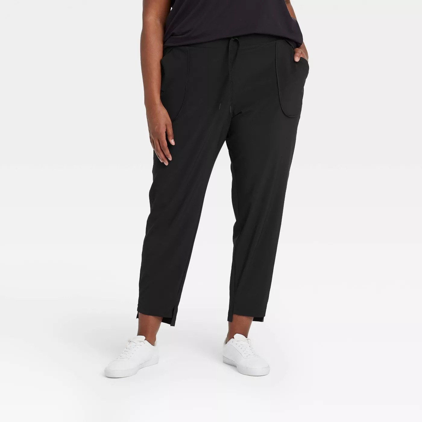 Model wearing loose black pants with side pockets, stop at the ankle