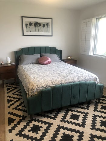 reviewer photo of their green bed frame with bedding on it