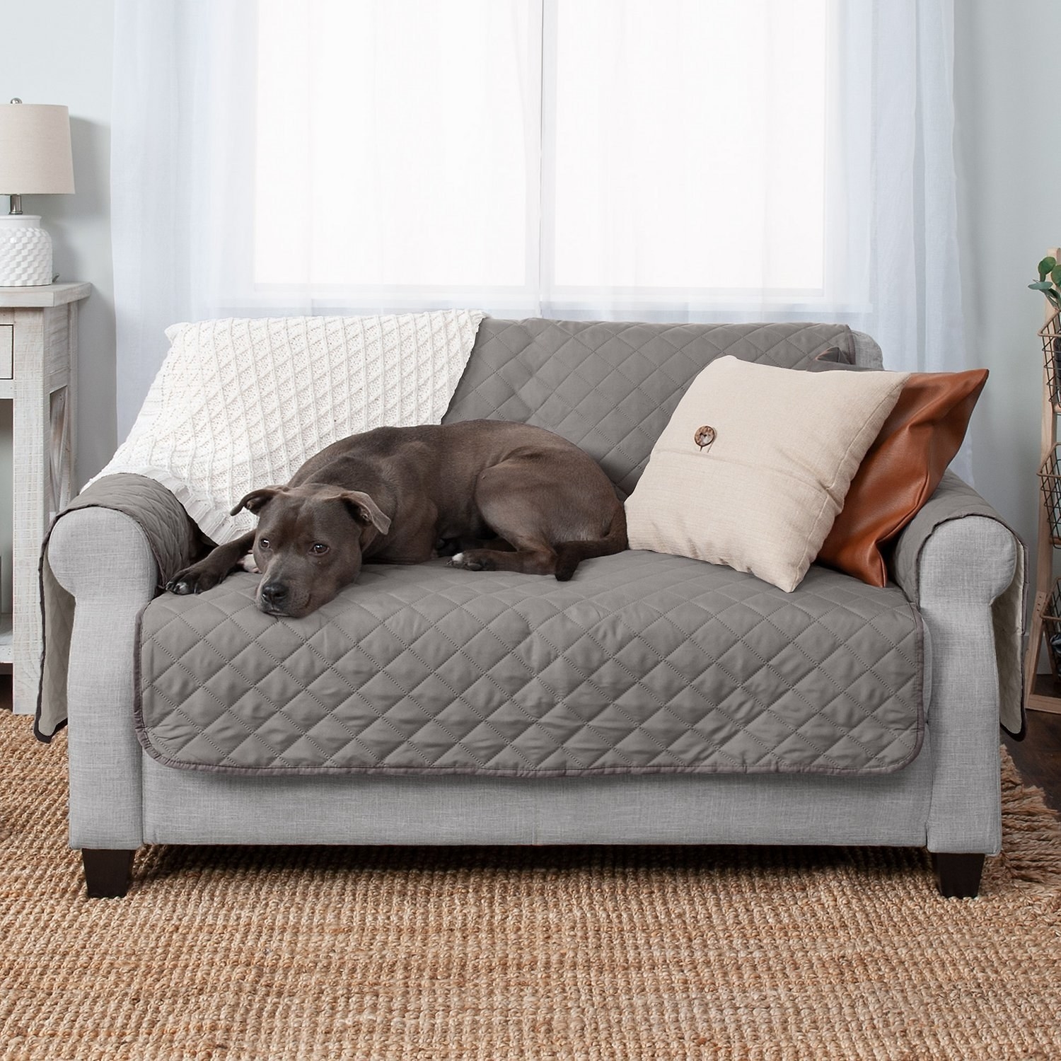 A dog sleeping on the loveseat protector in gray