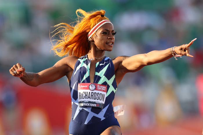 Sha'Carri pointing at her time as she crosses the finish line