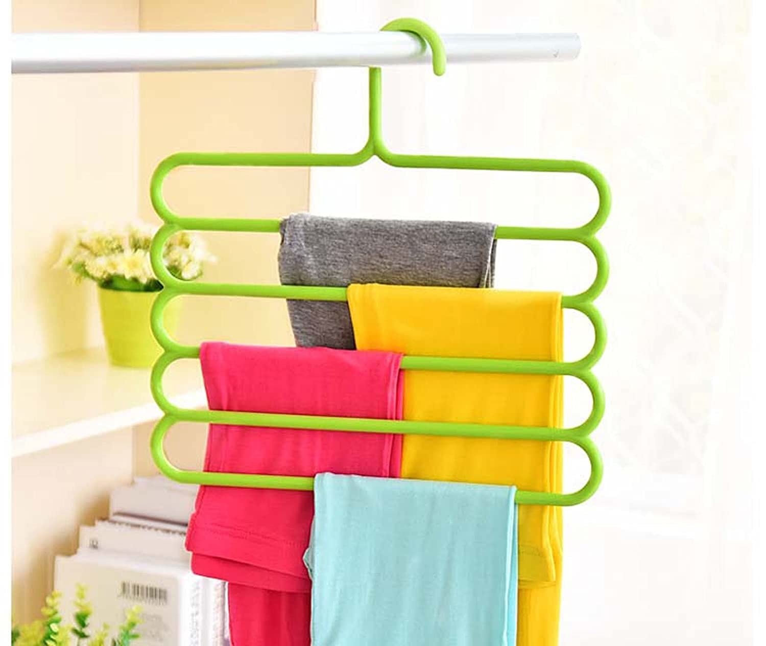 A green multi-tier hanger with clothes on it.