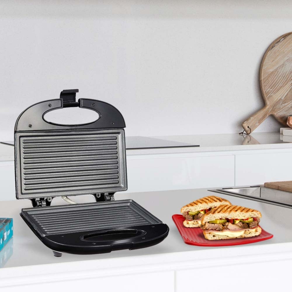 A sandwich maker with a grilled sandwich on the side