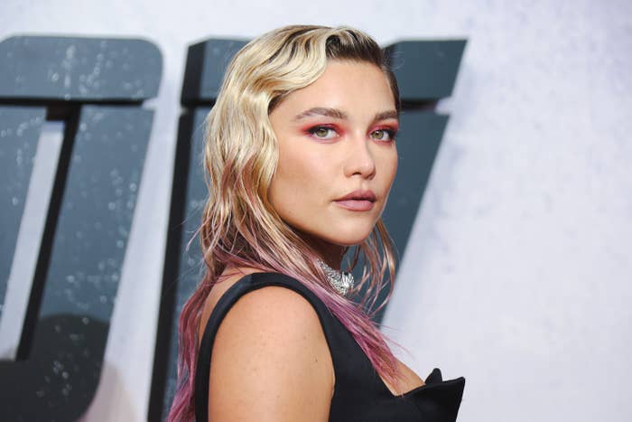 Florence Pugh, with hair of several tones, turns her head and looks at the camera