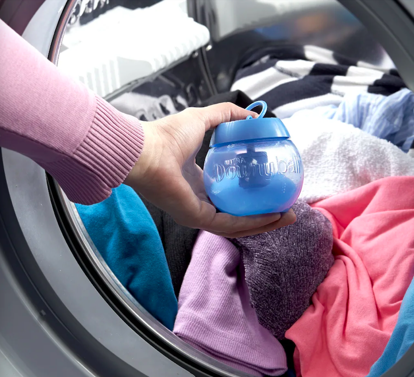 A person putting the ball into their washing machine