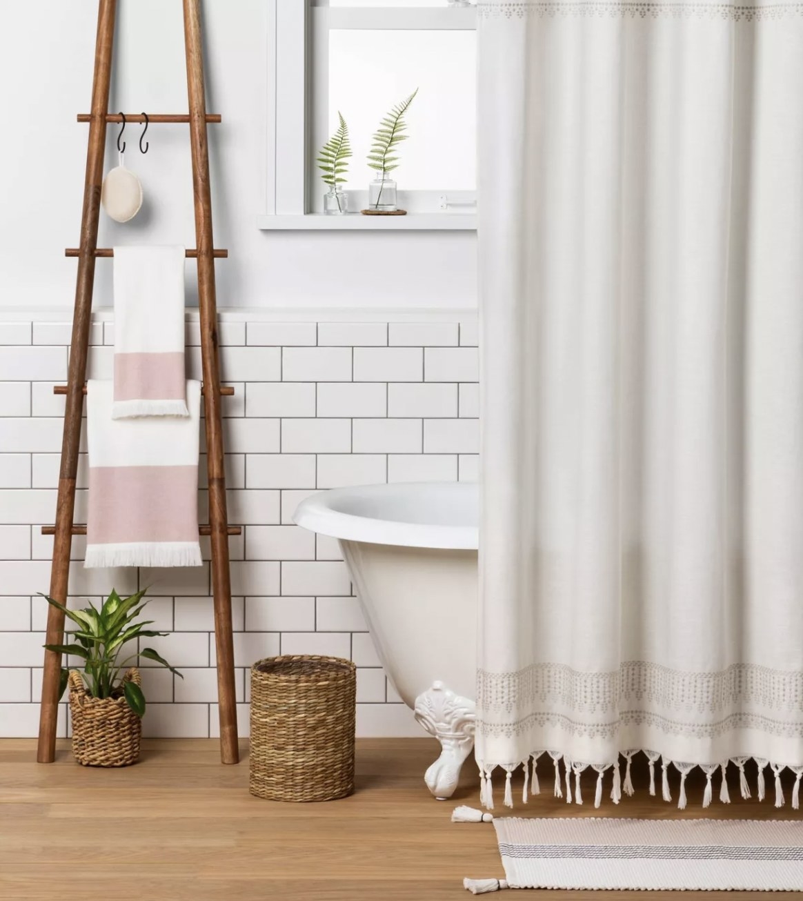 a ladder with four rings and s-shaped hooks holding towels and a loofah