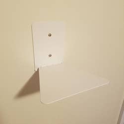 a reviewer photo of a white floating bookshelf mounted on a wall 