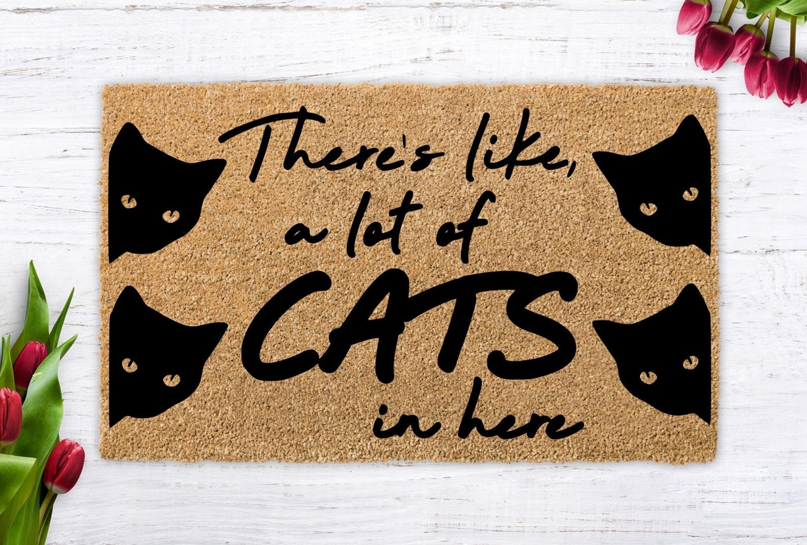 A welcome mat with four black cats and the words &quot;There&#x27;s like, a lot of cats in here&quot; on it