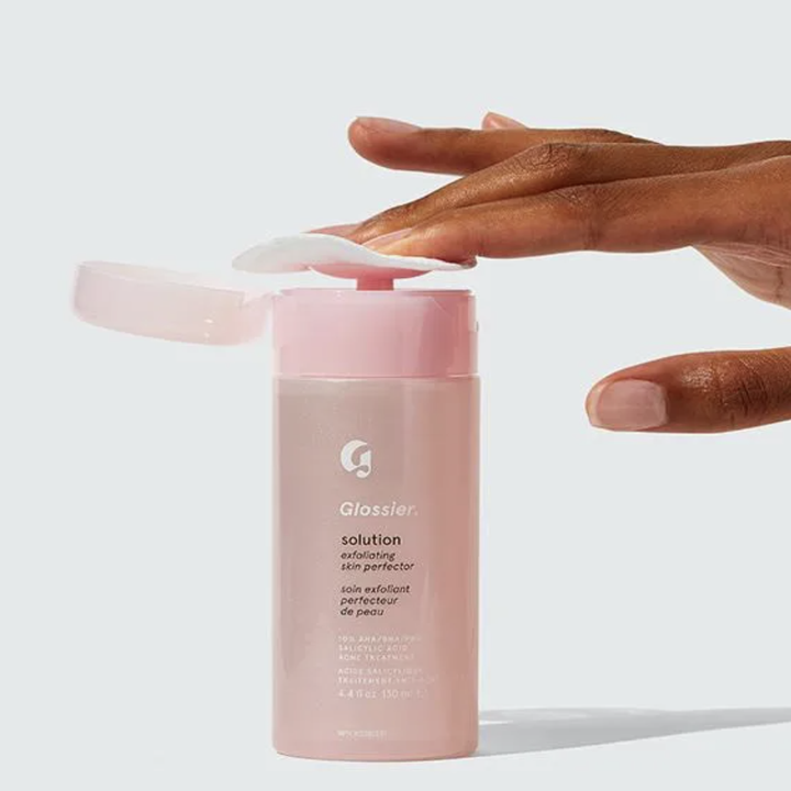 Model placing cotton pad over top of solution bottle