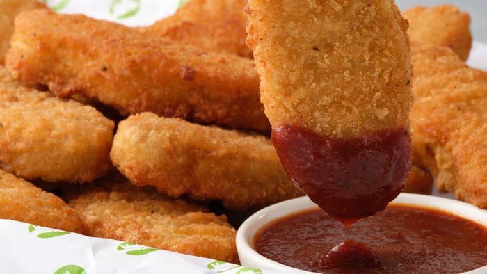 chicken tenders being dipped in barbecue sauce