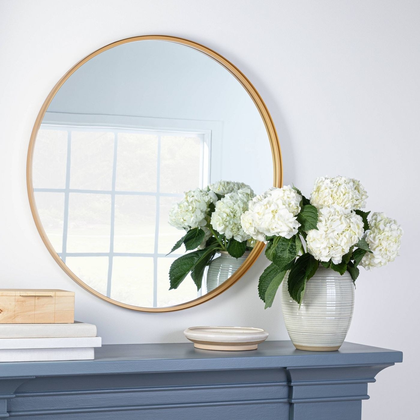 A round decorative mirror hanging above a mantle