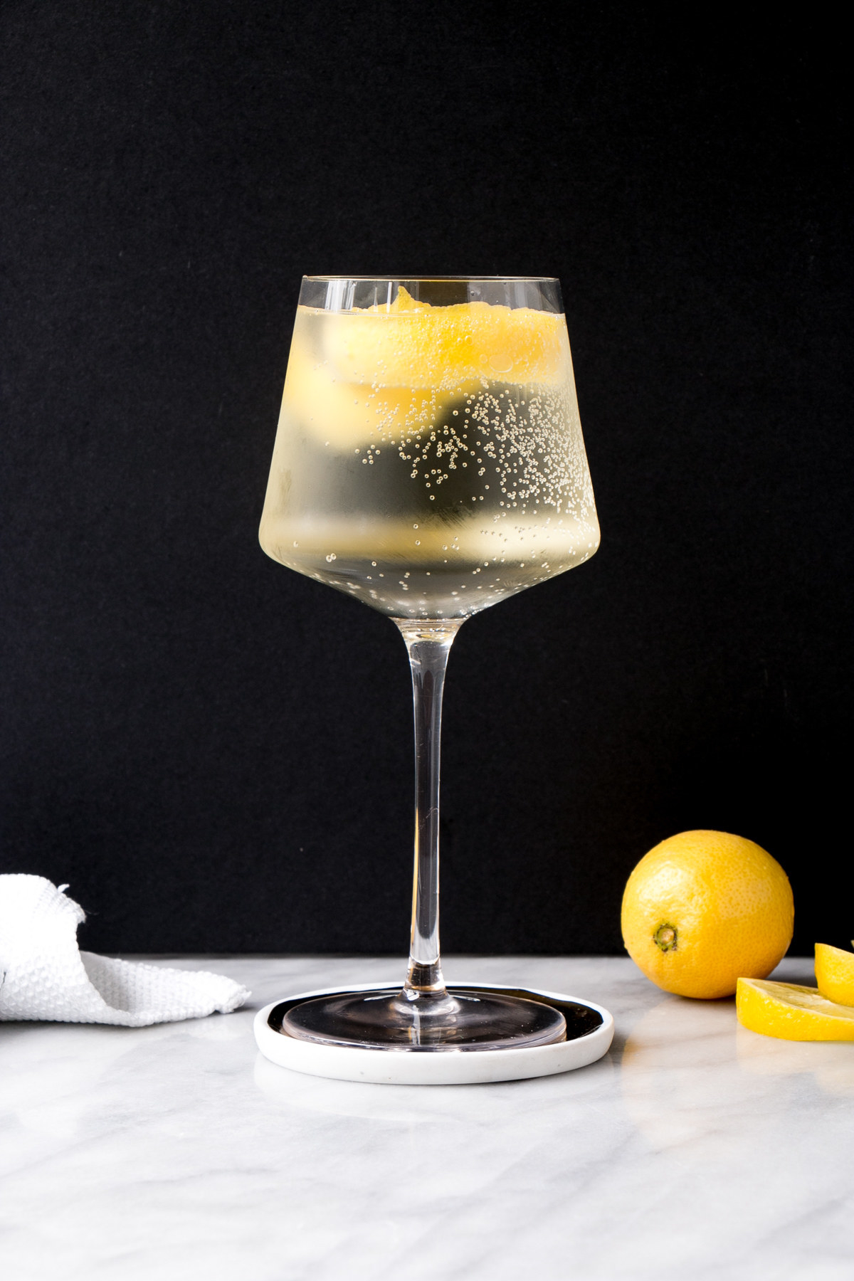 White wine spritzer in a wine glass garnished with lemon peel.