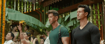 Tiger shroff and hrithik roshan walk into a wedding in which flowers are being strewn around, probably on the bride and groom
