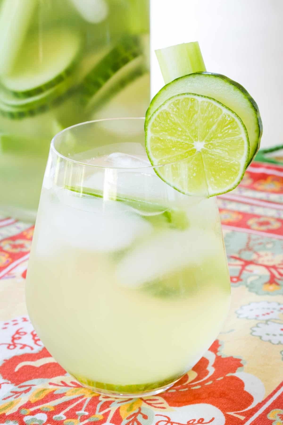 A light green cocktail in a stemless wineglass garnished with a slice of lime. 
