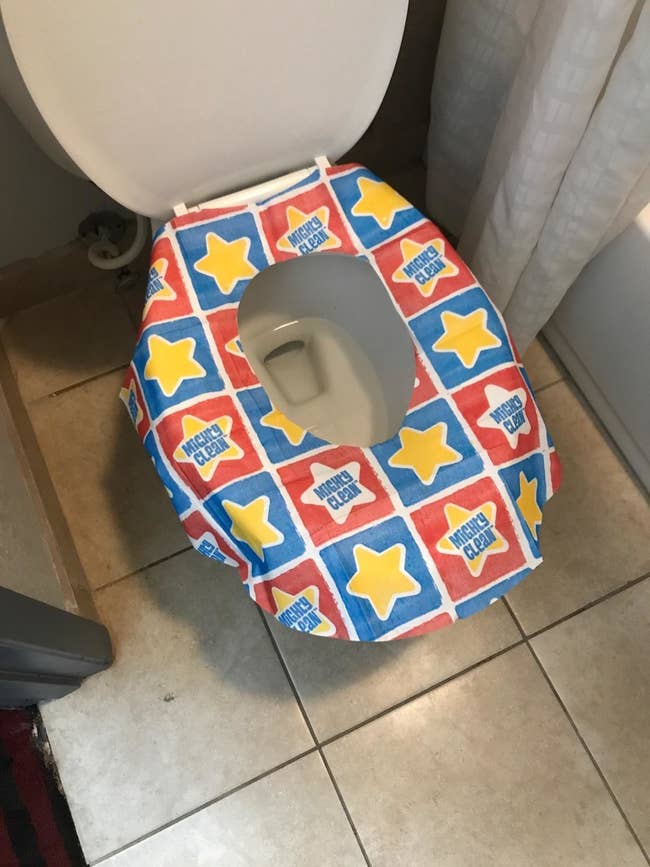 Reviewer's showing the red, blue, and yellow seat cover on a toilet