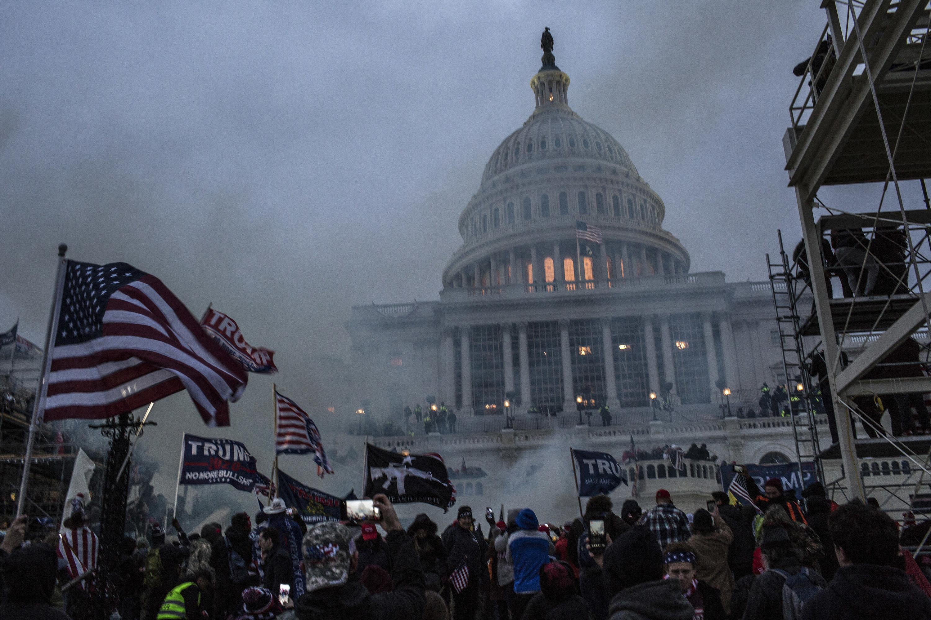 The Capitol, covered in gas and surrounded by Trump flags, at dusk