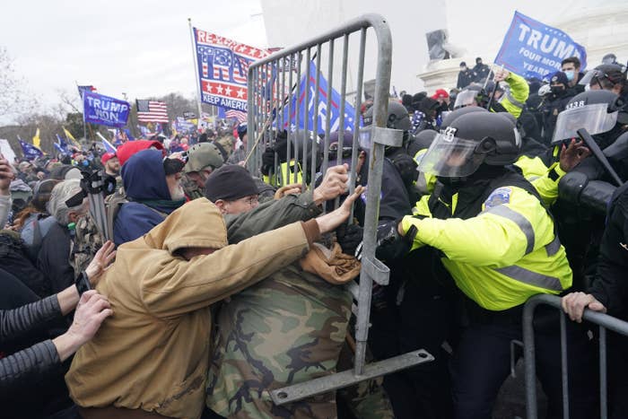 Trump supporters push a metal gate into a line of a police