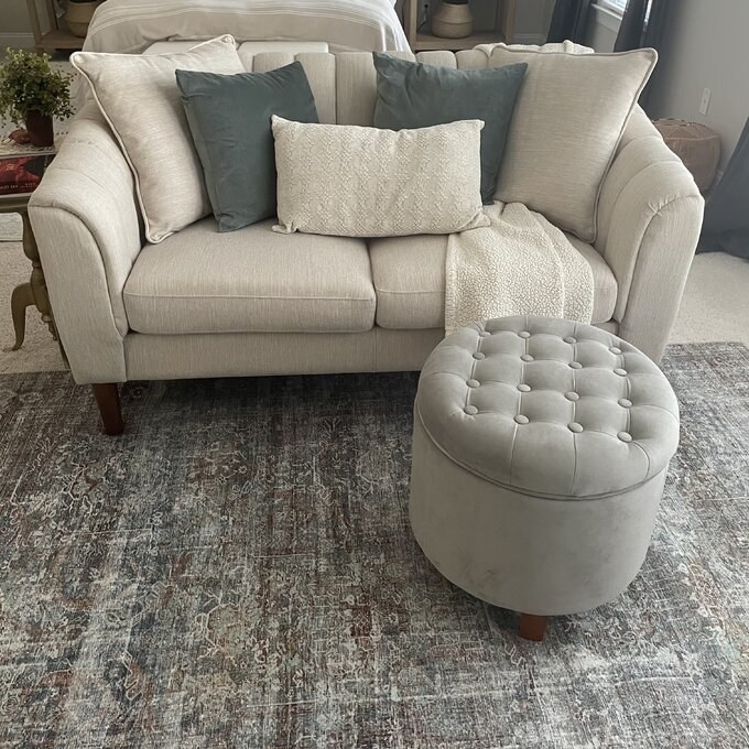 the grey ottoman next to a beige couch