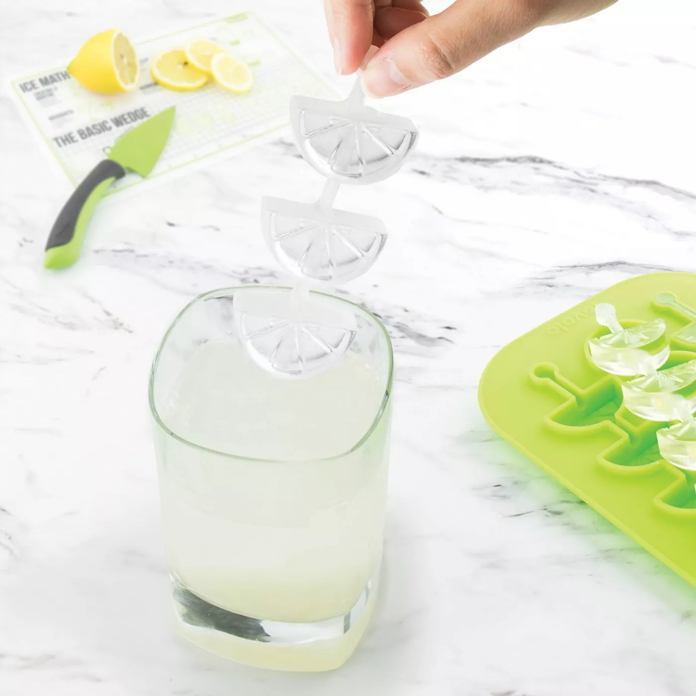 The three-tiered citrus ice cube is over a glass of what looks like lemonade