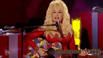 An animation (gif) of Dolly Parton in a glittery red and gold outfit, wearing red lipstick, playing a shiny rainbow-colored guitar 