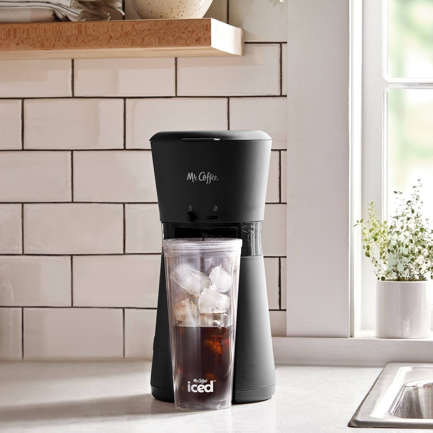 black iced coffee maker with a cup full of ice and coffee underneath