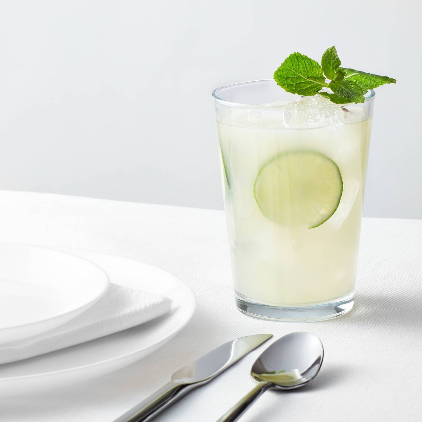 glass tumbler on a table filled with liquid and a lime slide inside