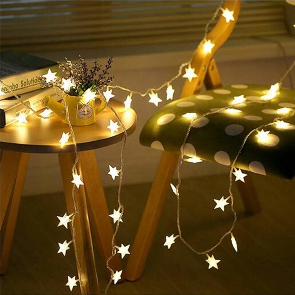 Starry string lights on a table with books on it next to a chair