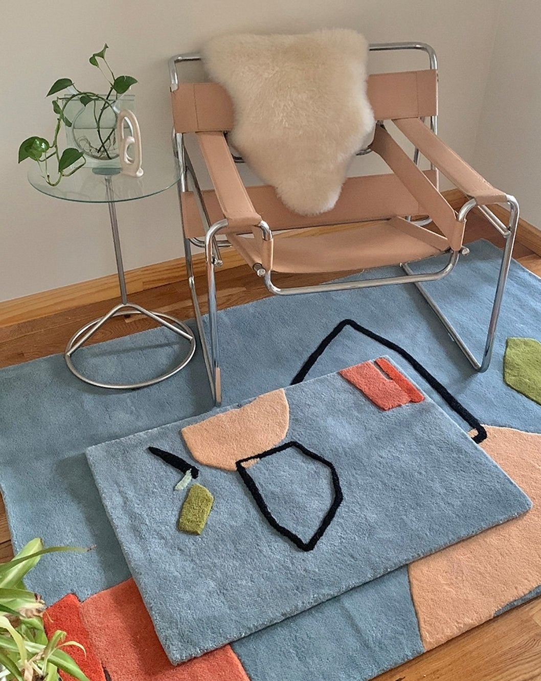 a small "limits of communication" wool rug on top of a larger one