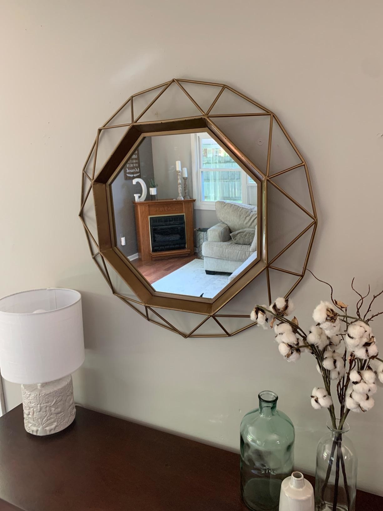 reviewer image of the gold geometric mirror hanging on a wall above a credenza