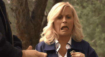 Amy Poehler eating food and making a disgusted expression.
