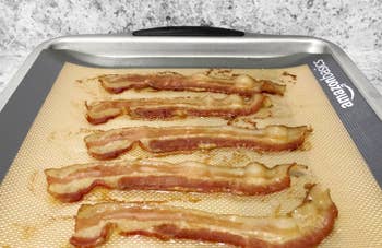 A customer review photo of a cookie sheet with the mats and freshly cooked bacon