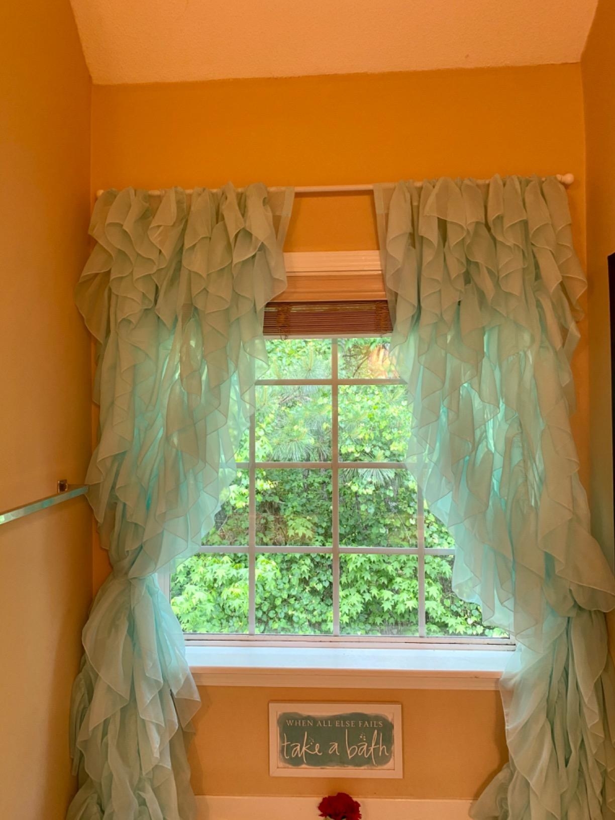 reviewer image of the sea blue ruffled curtains in a bathroom