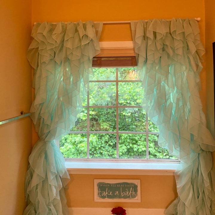 reviewer image of the sea blue ruffled curtains in a bathroom