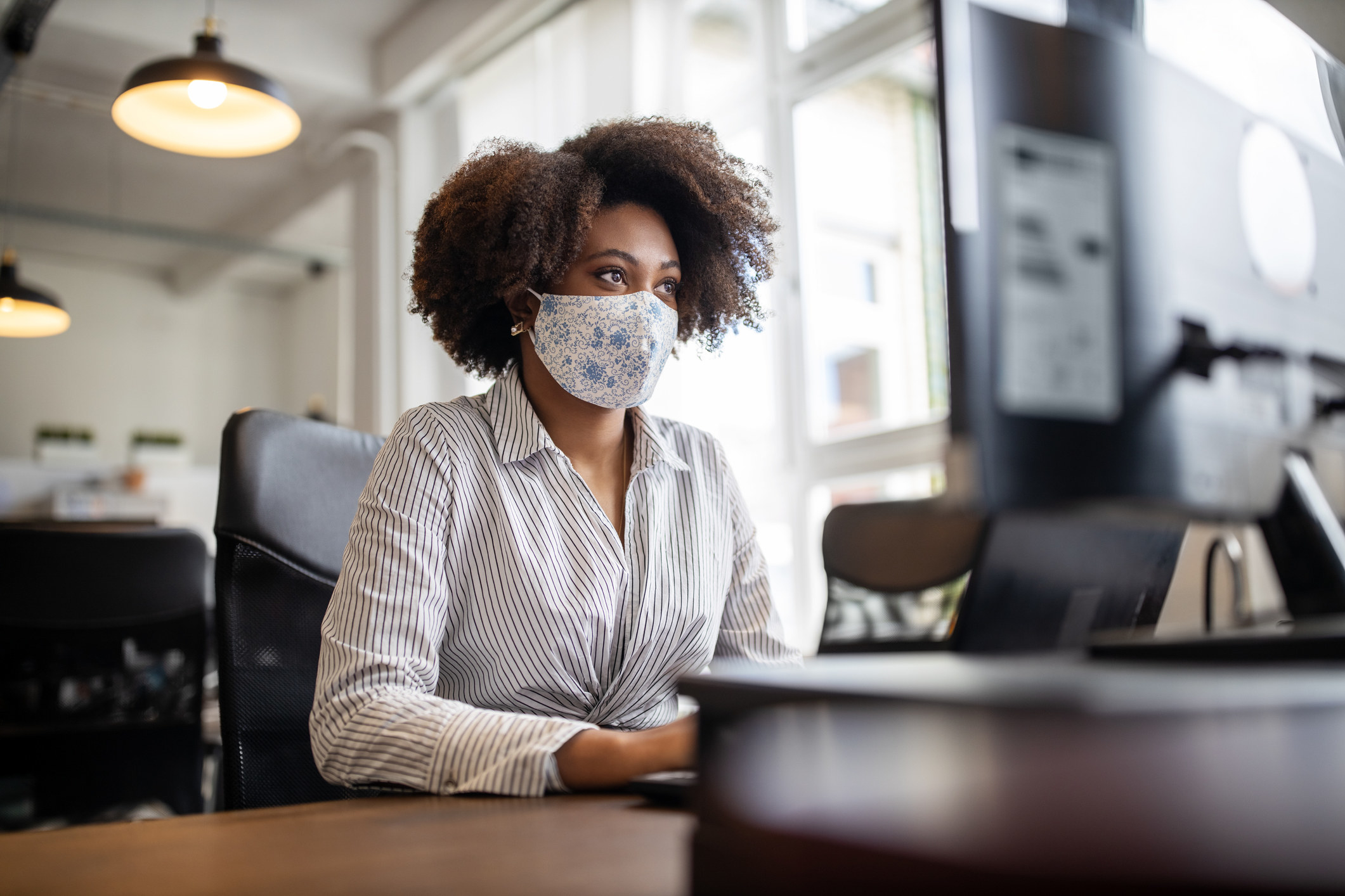 woman with a mask on looking at a computer screen