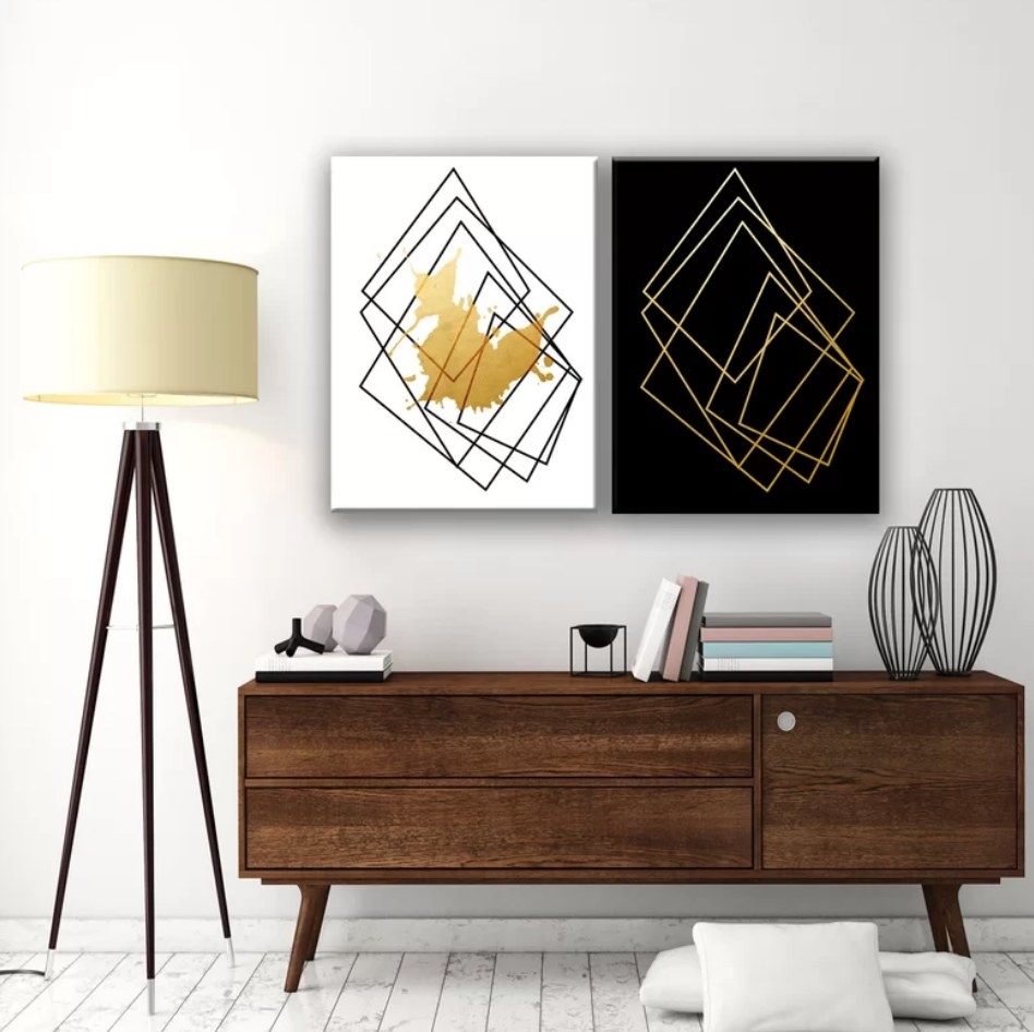 A two-piece, wrapped canvas graphic art print set in black, white, and gold hung up over a sideboard
