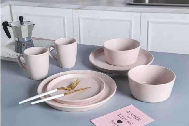 A pink, 32-piece dinnerware set that serves 8 placed on a kitchen island