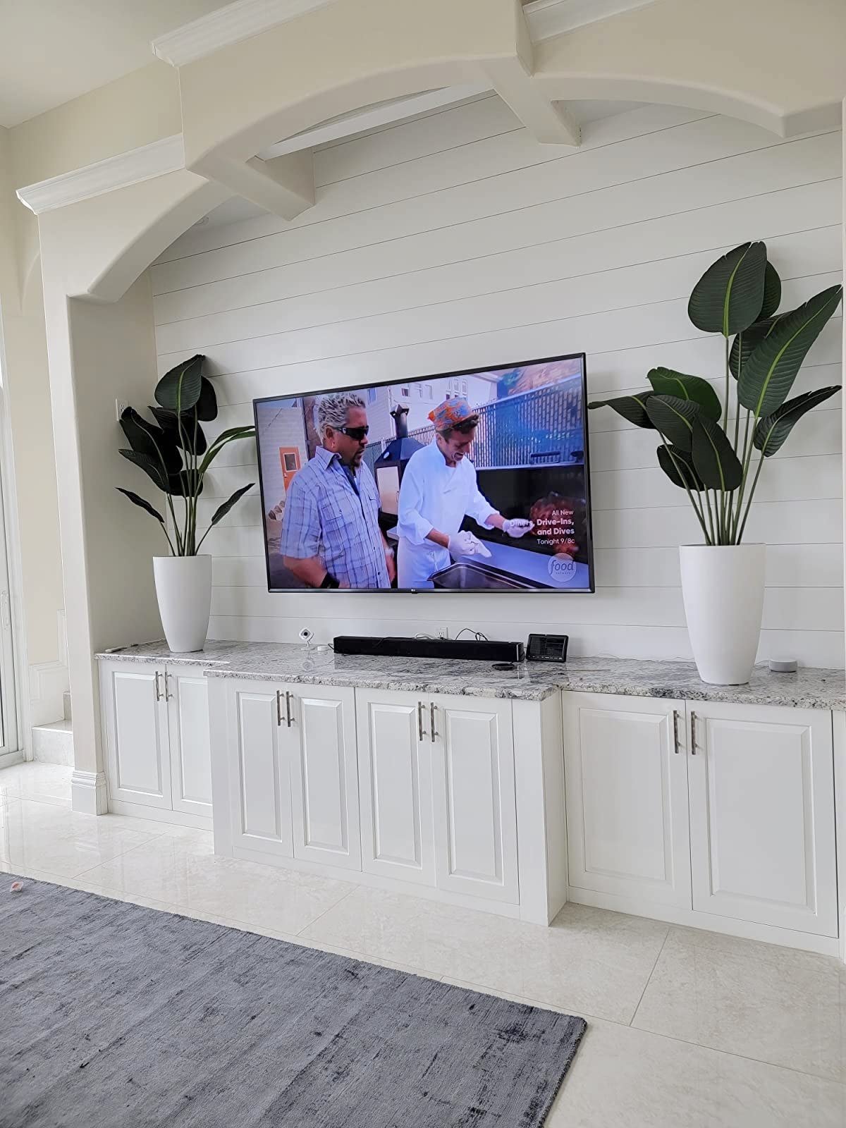 Reviewer&#x27;s two tall white planters sit on a cabinet between a television