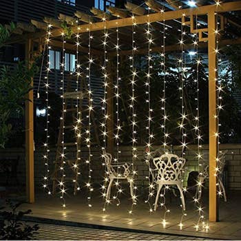 a pergola with ten vertical strands of string lights hanging form it 