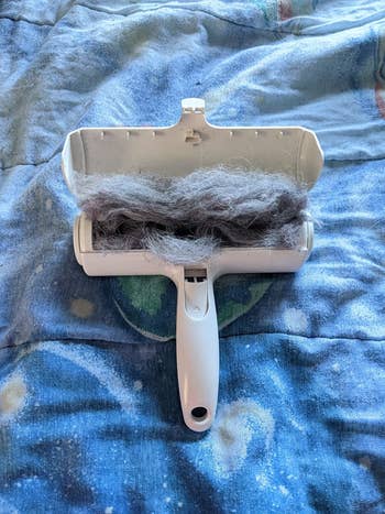 A reviewer's chom chom roller open to reveal all the collected pet hair inside