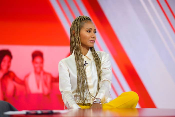 Jada Pinkett Smith sits with her leg crossed on her lap while filming Red Table Talk