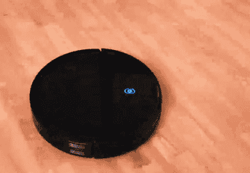 GIF of reviewer&#x27;s robo vac moving across a wooden floor