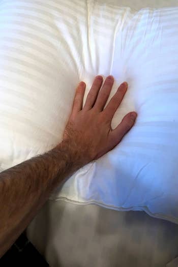 a reviewer's hand pressing down on the pillow 