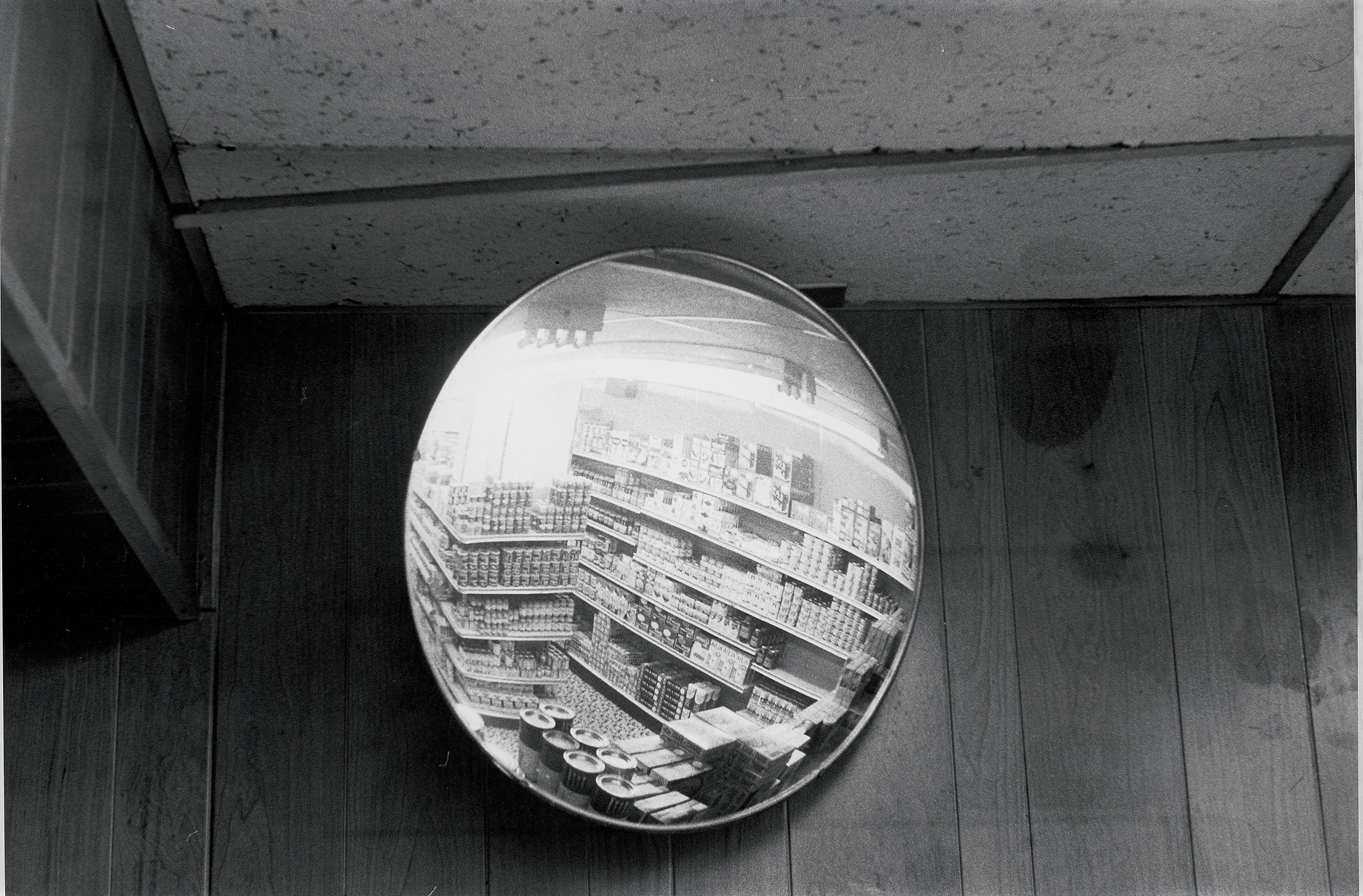 A surveillance mirror showing aisles of goods against a plain wall