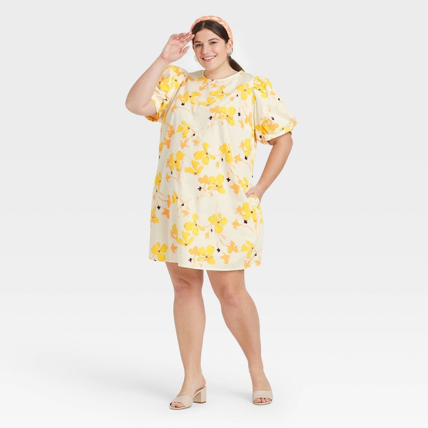 A model wearing a cream and yellow flower print dress with puff sleeves