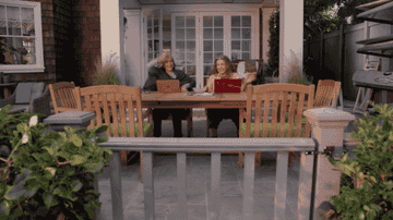 Grace and Frankie sitting at their laptops on their patio