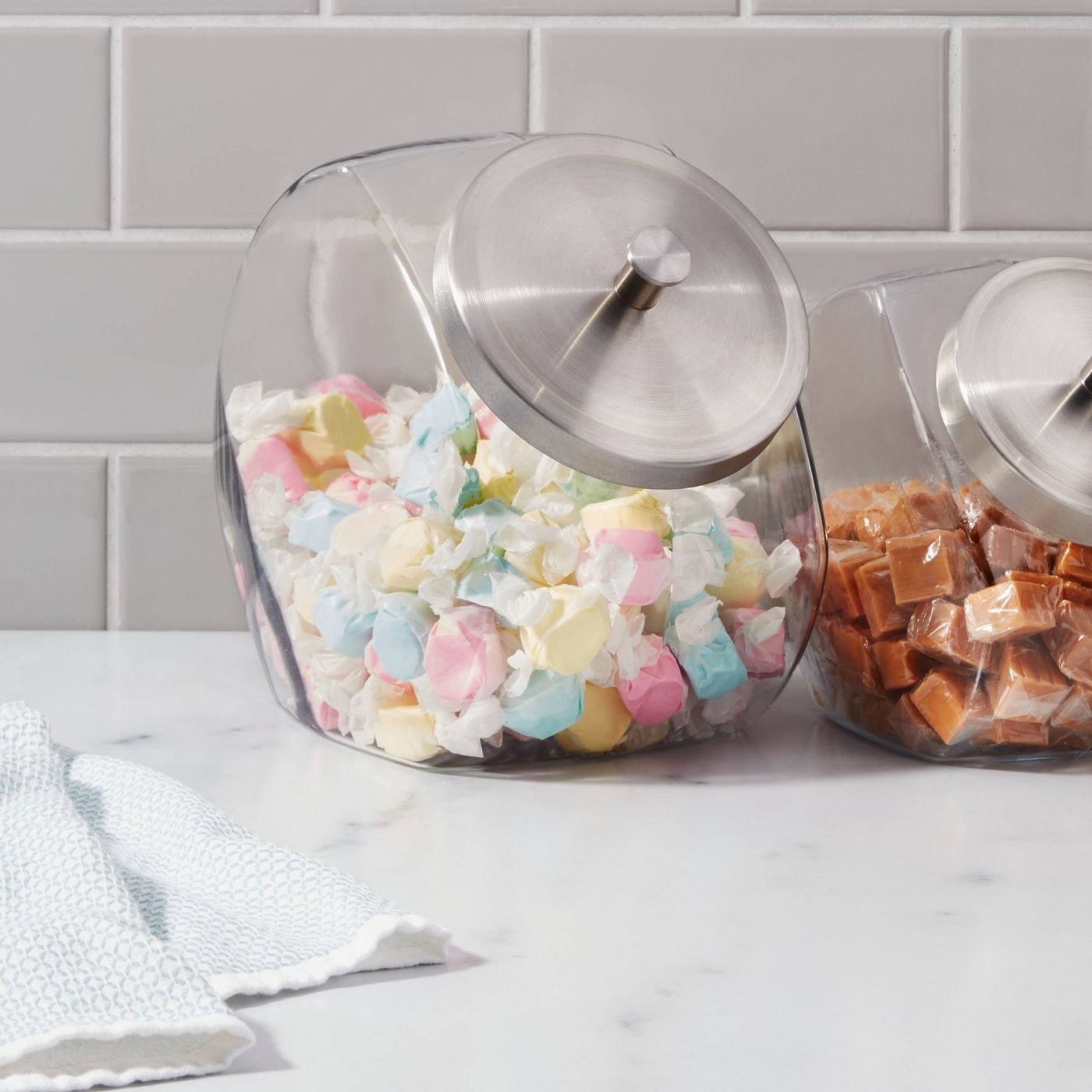 a glass candy jar with a metal lid filled with candy