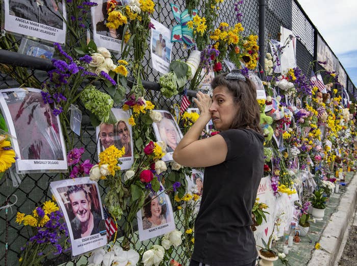 A woman cries in front of a memorial with flowers and pictures of victims