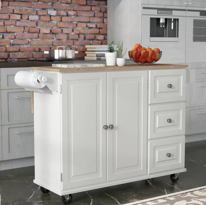 White kitchen cart with light wooden top and paper towel holder on side