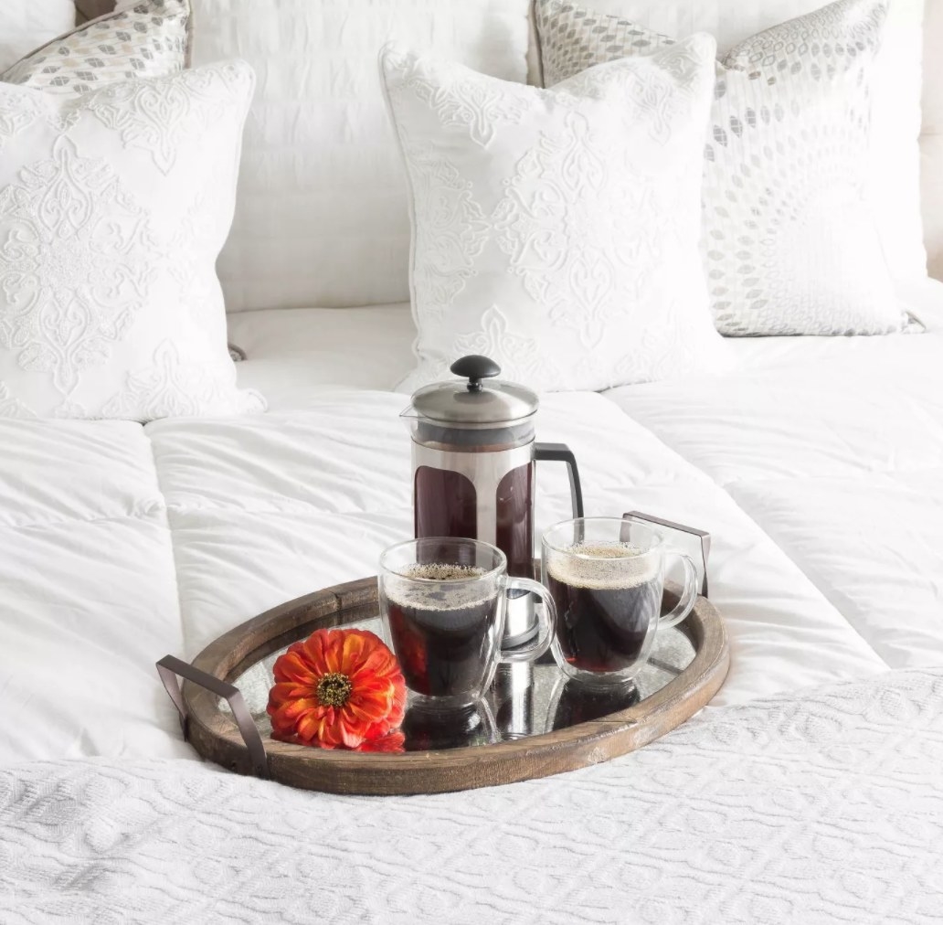 The tray with a coffee pot and flower on top of a bed